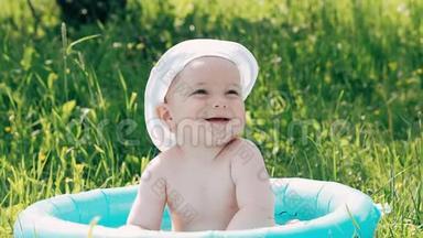 小男孩宝宝在一个充气的游泳池里洗澡，在夏天微笑肥皂泡